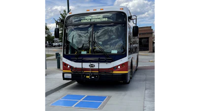 Municipal bus approaching a wireless inductive charging pad.