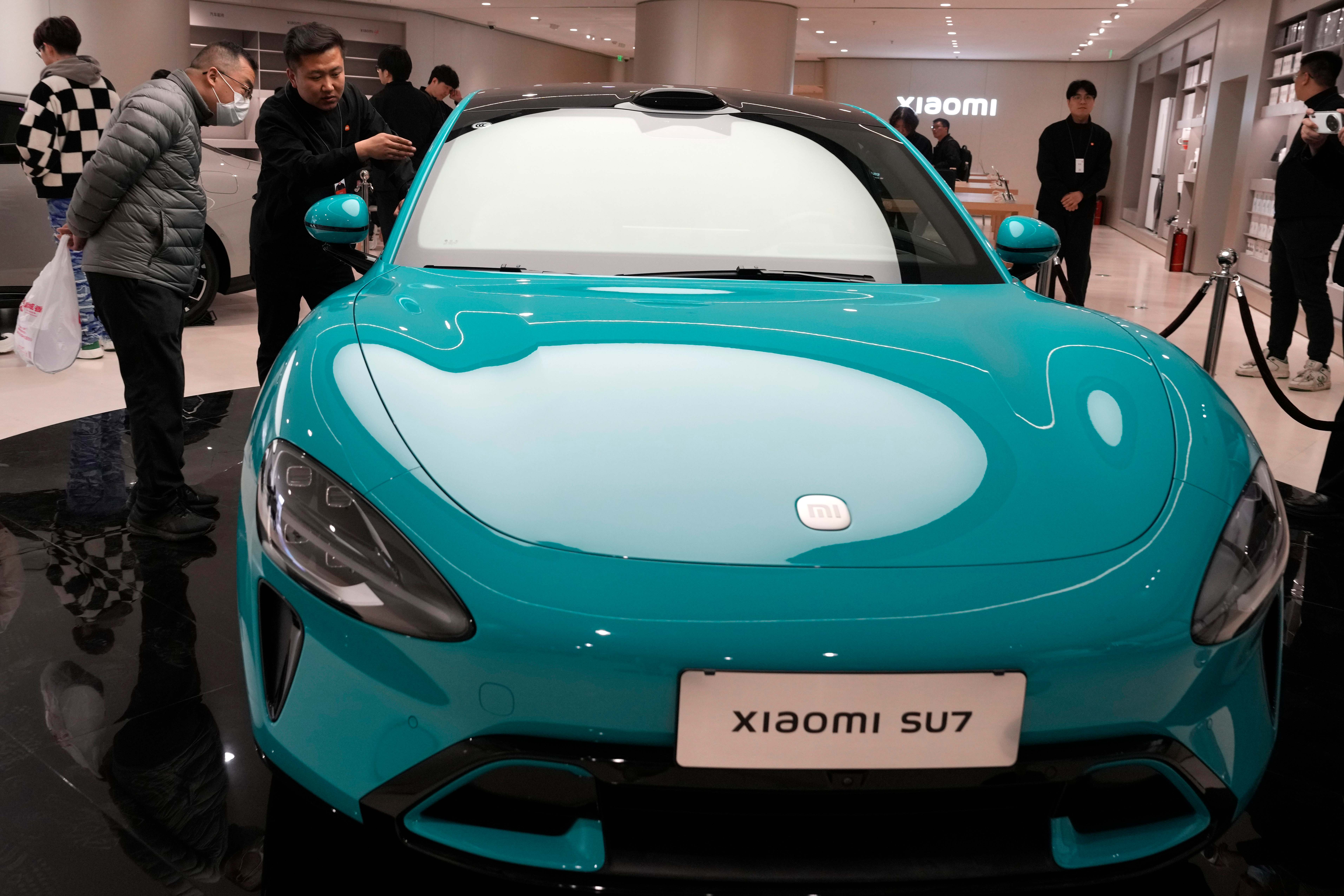 Visitors to the Xiaomi Automobile flagship store look at the Xiaomi SU7 electric car on display in Beijing, Tuesday, March 26, 2024.