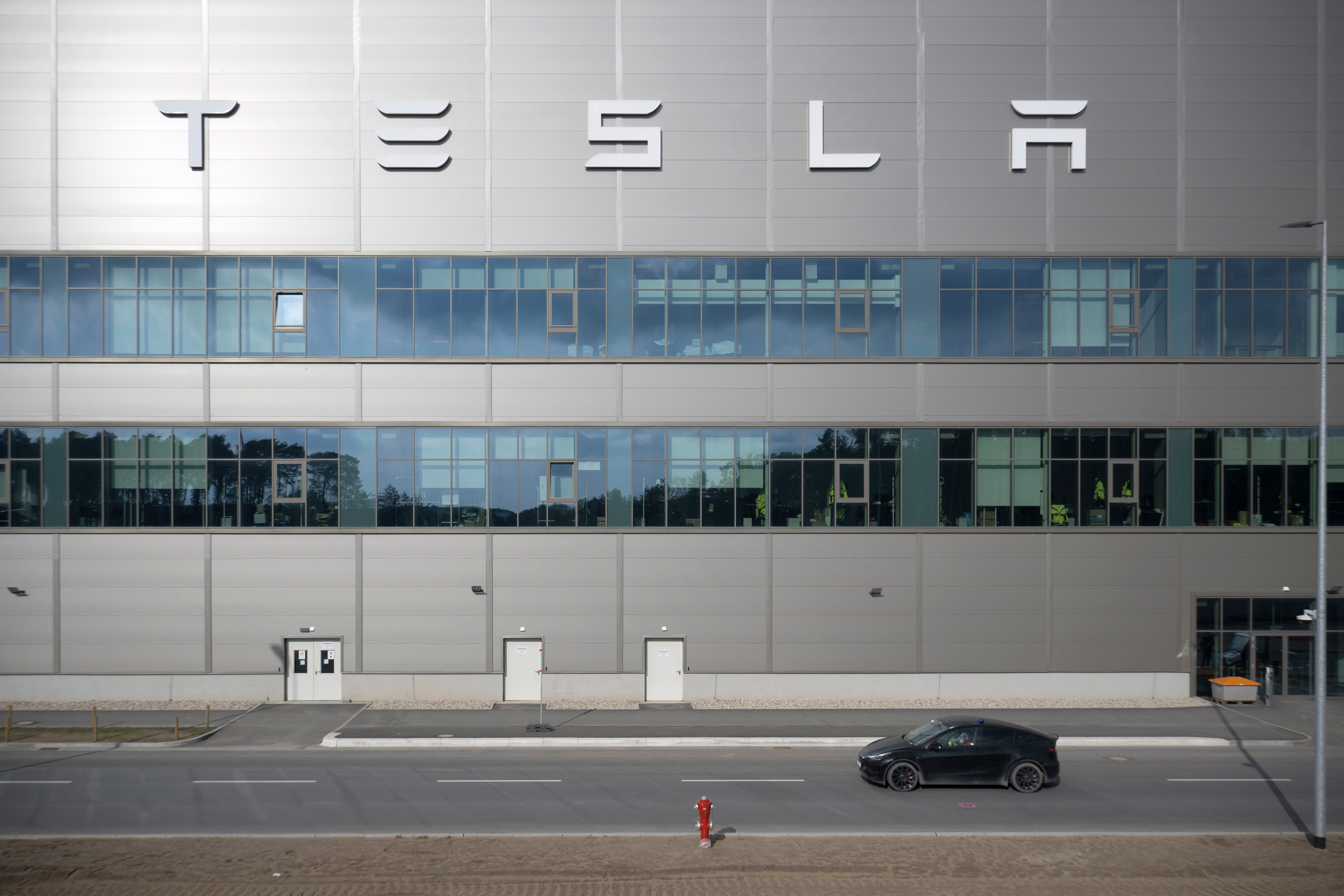 A vehicle from the security service drives by the Tesla car factory after production came to a standstill and workers were evacuated following a power outage, in Grünheide, Germany, Tuesday, March 5, 2024.