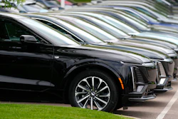 Vehicles sit in a row outside a dealership.