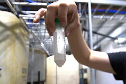 Dave Hoffman of West Virginia University's Water Research Institute holds up a vial of light rare earth oxides at a facility that separates them from acidic groundwater draining from an abandoned coal mine, June 25, 2024, in Mount Storm, W.Va.
