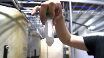 Dave Hoffman of West Virginia University's Water Research Institute holds up a vial of light rare earth oxides at a facility that separates them from acidic groundwater draining from an abandoned coal mine, June 25, 2024, in Mount Storm, W.Va.