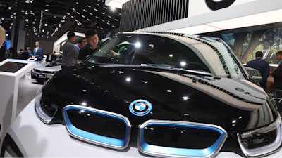 A worker cleans an electric vehicle at the BMW booth during the Auto Shanghai 2019 show in Shanghai on April 17, 2019.