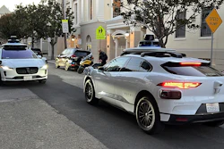 Two Waymo driverless taxis stop before passing one another on a San Francisco street on Feb. 15, 2023.