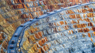 A dump truck convoy travels up through a copper mine.