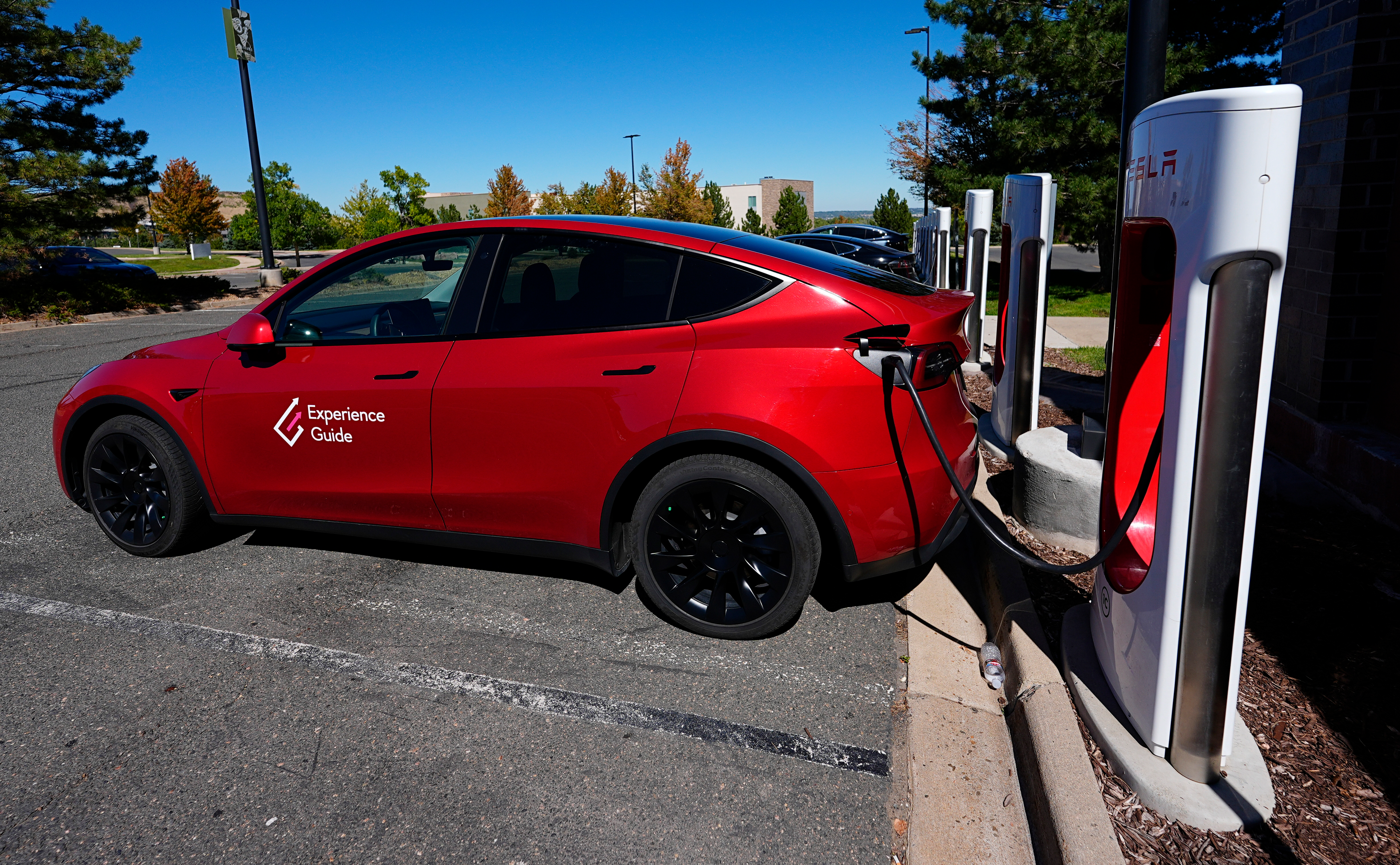 A Tesla Model 3 charges at a Tesla supercharging station situated in the parking lot of an outlet mall on Sept. 25, 2024, in Lakewood, Colo.