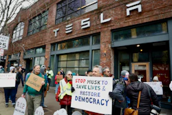 People protesting Elon Musk's actions in the Trump administration hold signs outside a Tesla showroom in Seattle on Thursday, Feb. 13, 2025.