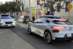 Two Waymo driverless taxis stop before passing one another on a San Francisco street on Feb. 15, 2023.