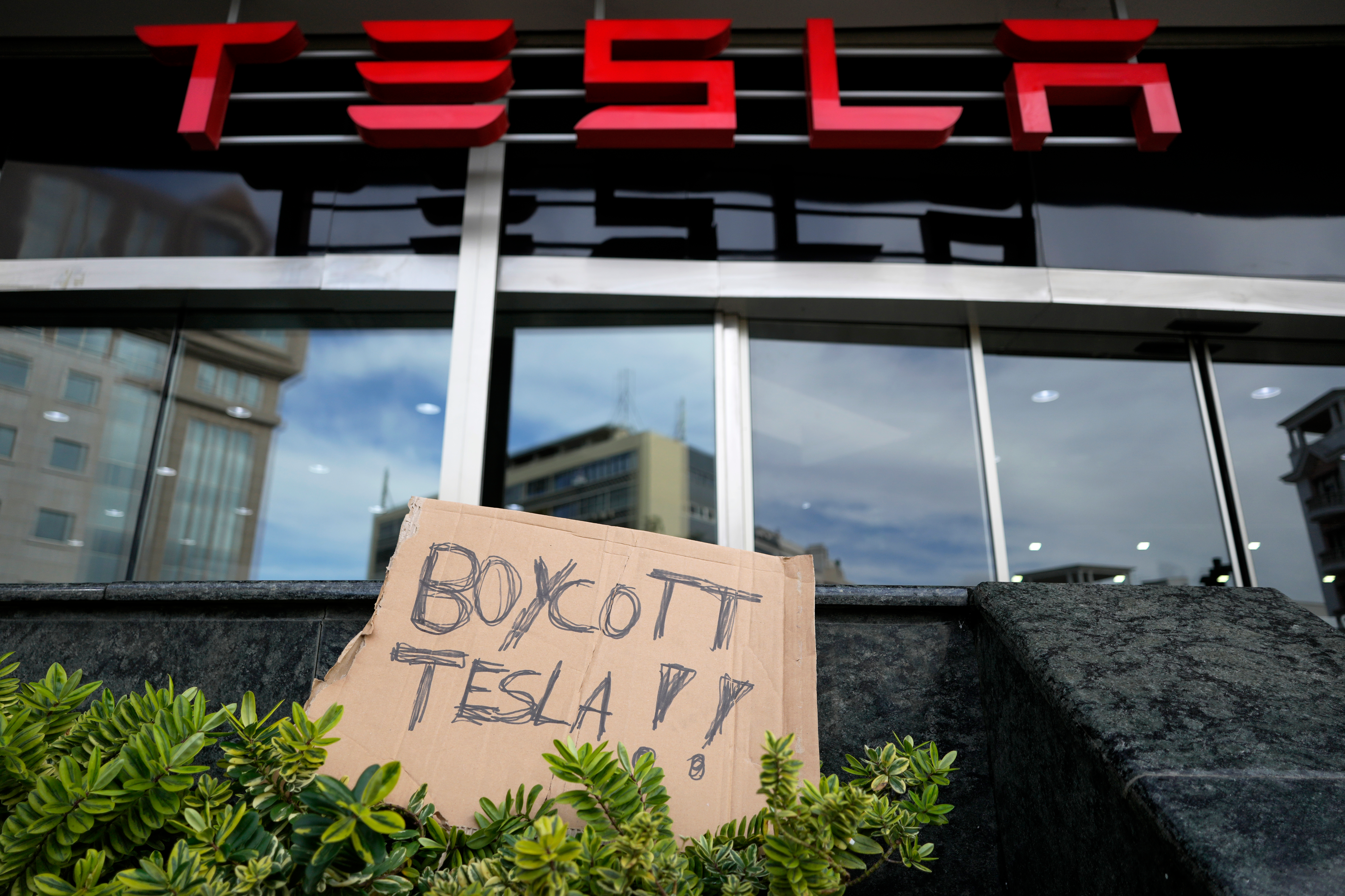 A banner is left outside a Tesla showroom during a demonstration, in Lisbon, Sunday, March 9, 2025.