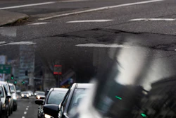 In this image taken through the reflection of a car window, a person walks along W Burnside Street near a repaired patch in the road on Thursday, Feb. 6, 2025, in Portland, Ore.
