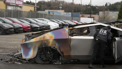 A member of the Seattle Fire Department inspects a burned Tesla Cybertruck at a Tesla lot in Seattle, Monday, March 10, 2025.