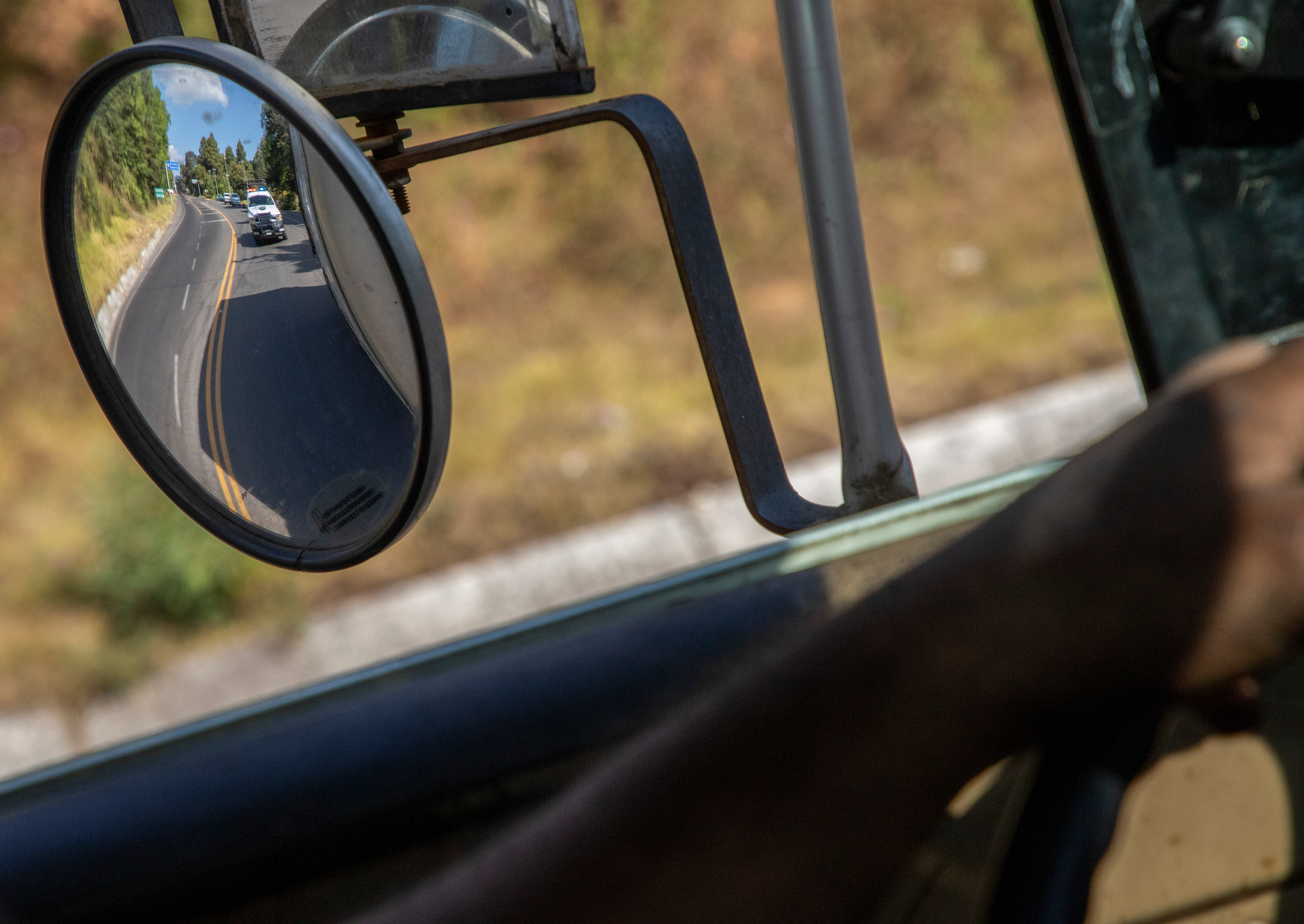 Trucks loaded with avocados are seen reflected on a rear view mirror as they are escorted by the police on their way to the city of Uruapan, in Santa Ana Zirosto, Michoacan state, Mexico, Jan. 26, 2023.