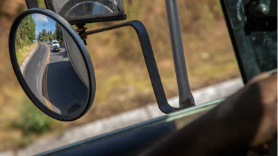 Trucks loaded with avocados are seen reflected on a rear view mirror as they are escorted by the police on their way to the city of Uruapan, in Santa Ana Zirosto, Michoacan state, Mexico, Jan. 26, 2023.