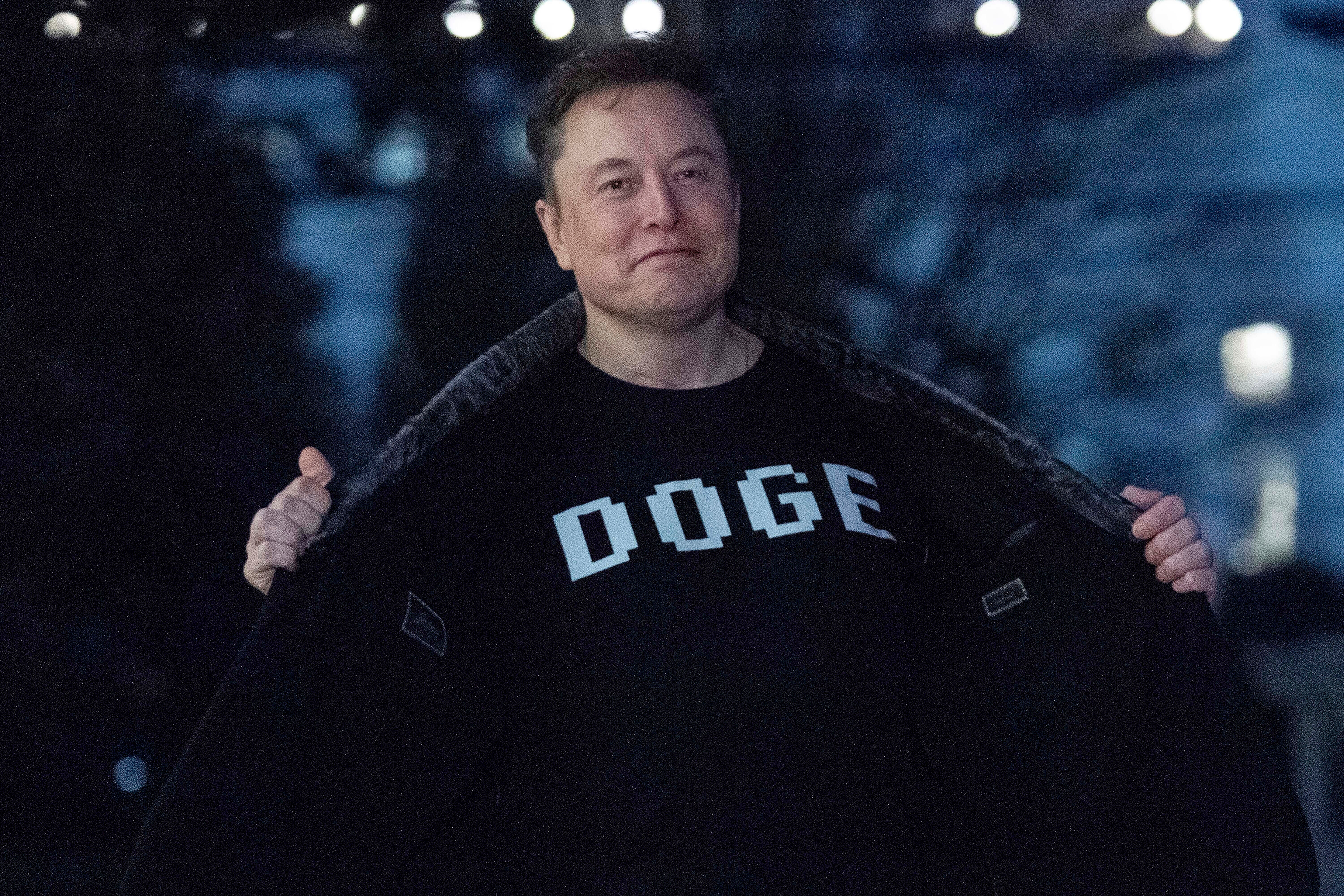 Elon Musk flashes his T-shirt that reads 'DOGE' to the media as he walks on South Lawn of the White House, in Washington, March 9, 2025.