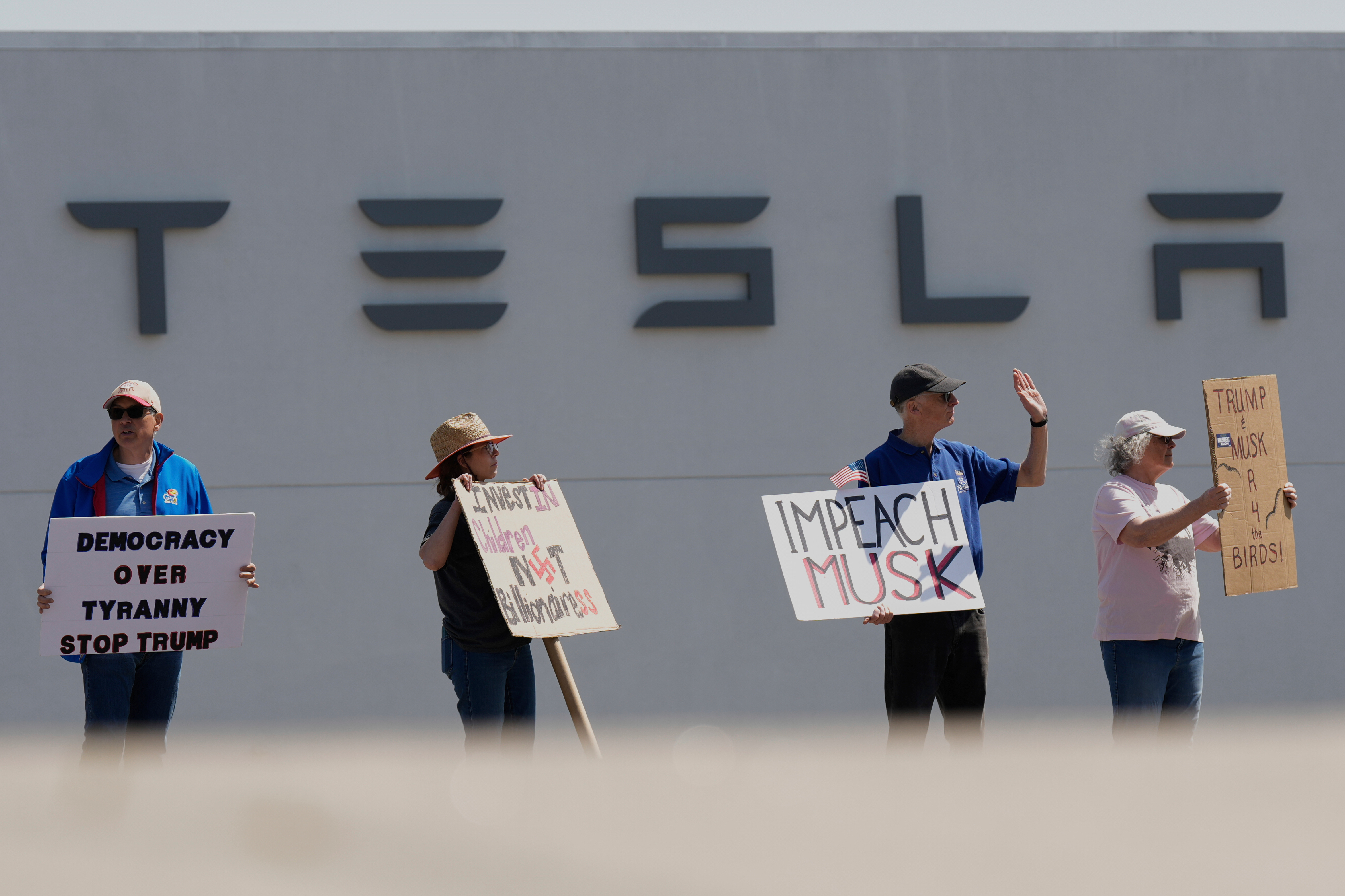 Demonstrators protest against Elon Musk and Department of Government Efficiency cuts outside a Tesla dealership, Saturday, April 12, 2025, in Kansas City, Mo.
