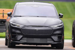 Black Ford Mustang Mach-E electric SUV parked on road with green background