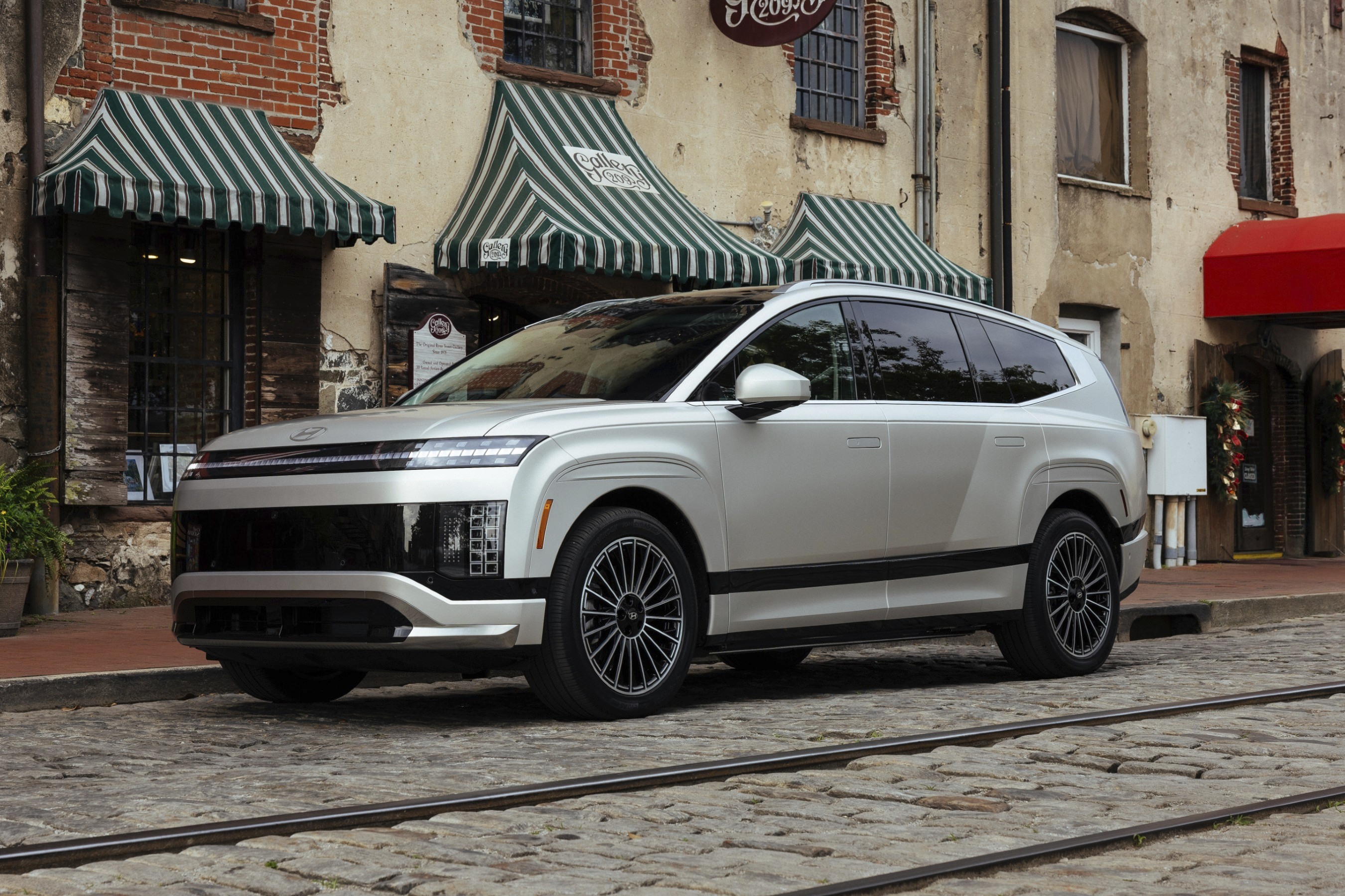 Silver Hyundai IONIQ 5 electric SUV parked on cobblestone street with brick buildings