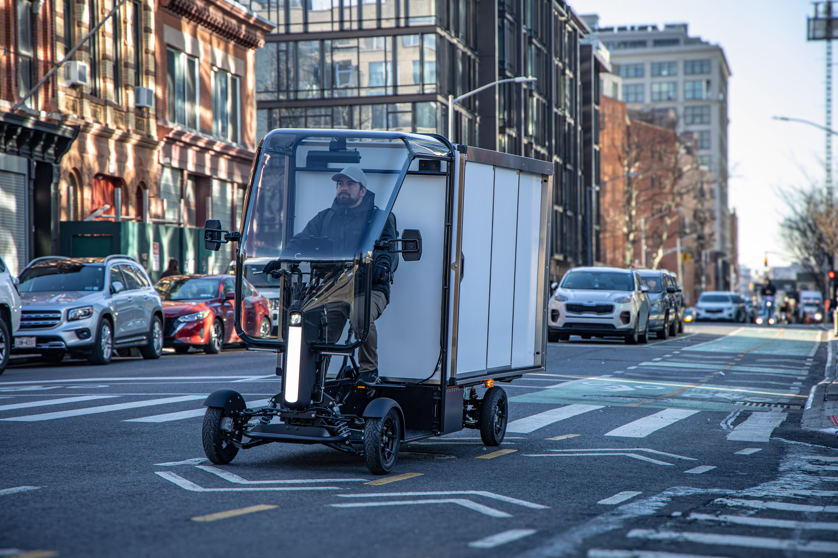 Enclosed electric delivery vehicle on city street with urban buildings