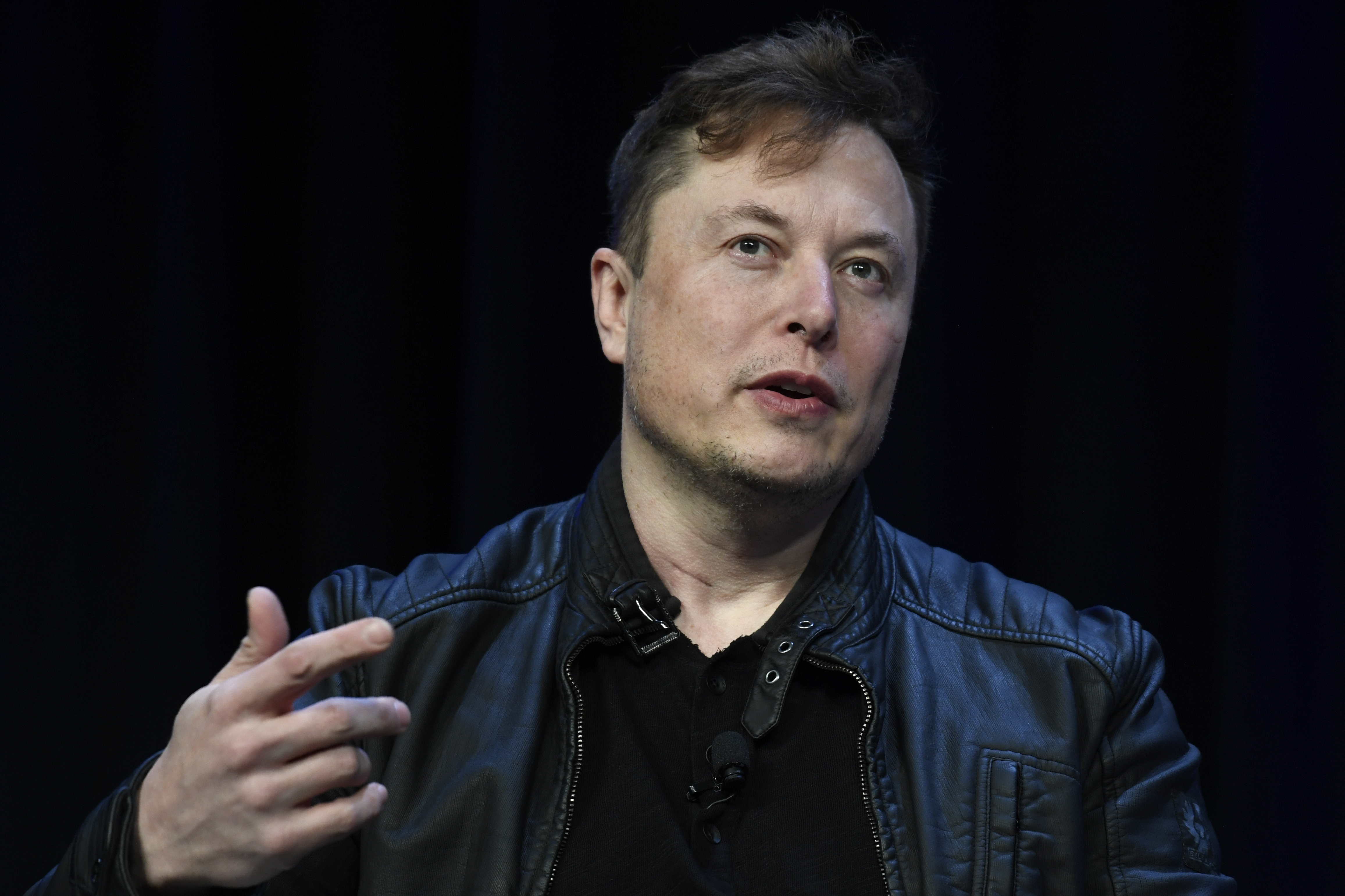Tech executive speaking at conference in black leather jacket