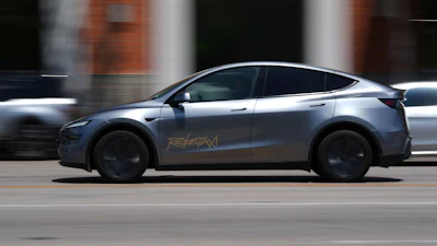 Silver Tesla electric SUV driving on urban street with blurred background