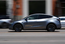 Silver Tesla electric SUV driving on urban street with blurred background