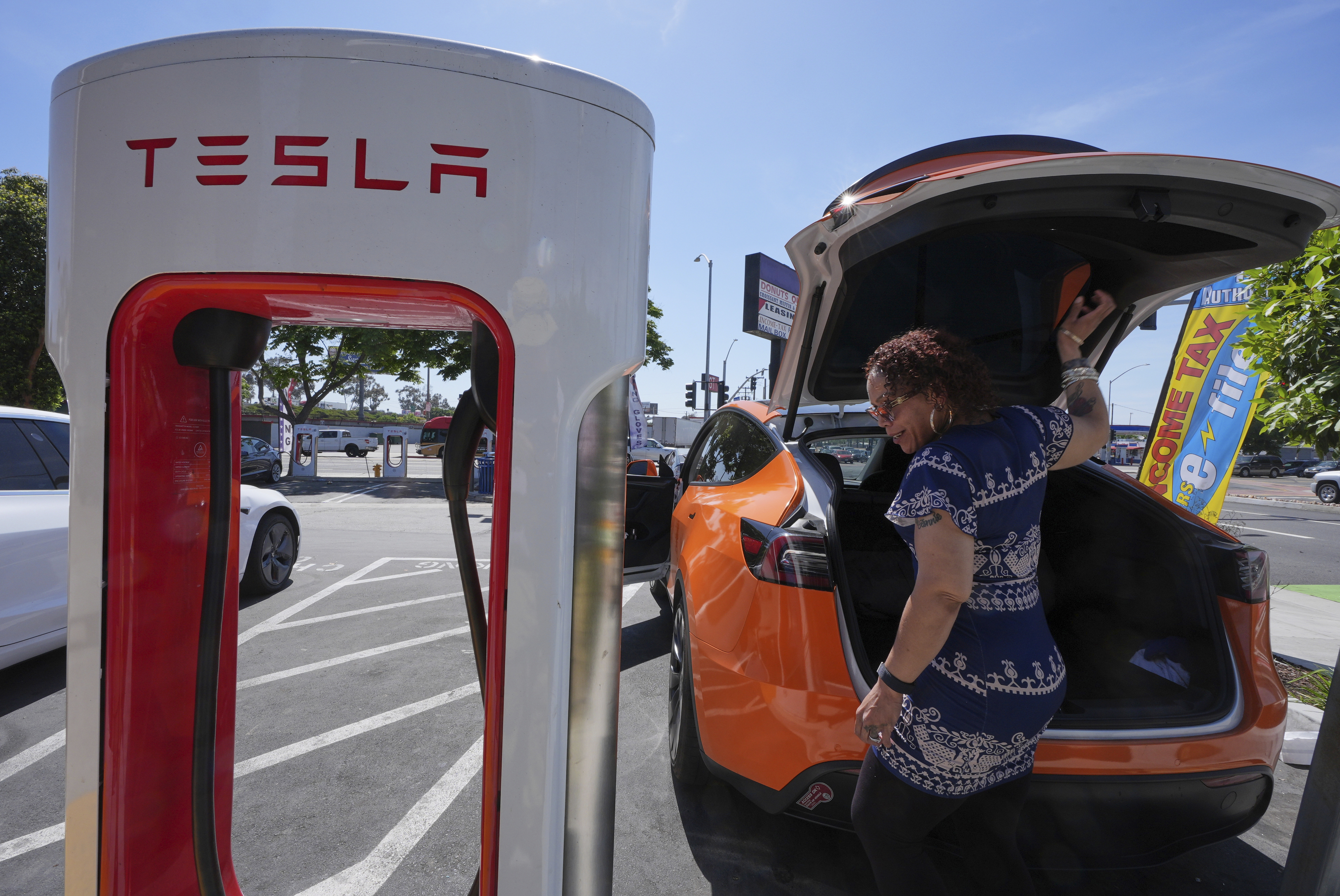 Tesla electric vehicle charging at a white and red Supercharger station