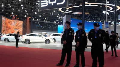 BYD automotive booth at car show with white vehicles and security personnel