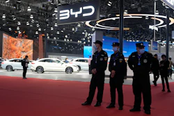 BYD automotive booth at car show with white vehicles and security personnel