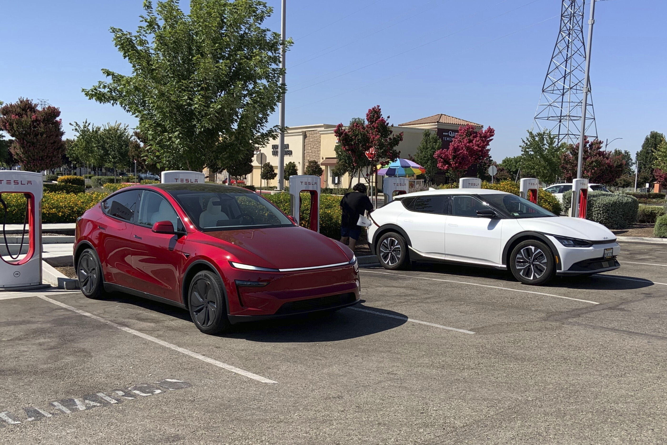 Red and white electric vehicles charging at Tesla Supercharger station
