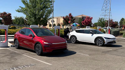 Red and white electric vehicles charging at Tesla Supercharger station
