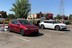 Red and white electric vehicles charging at Tesla Supercharger station
