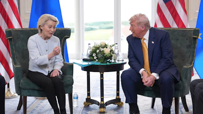 Two political leaders seated during bilateral meeting with US and EU flags