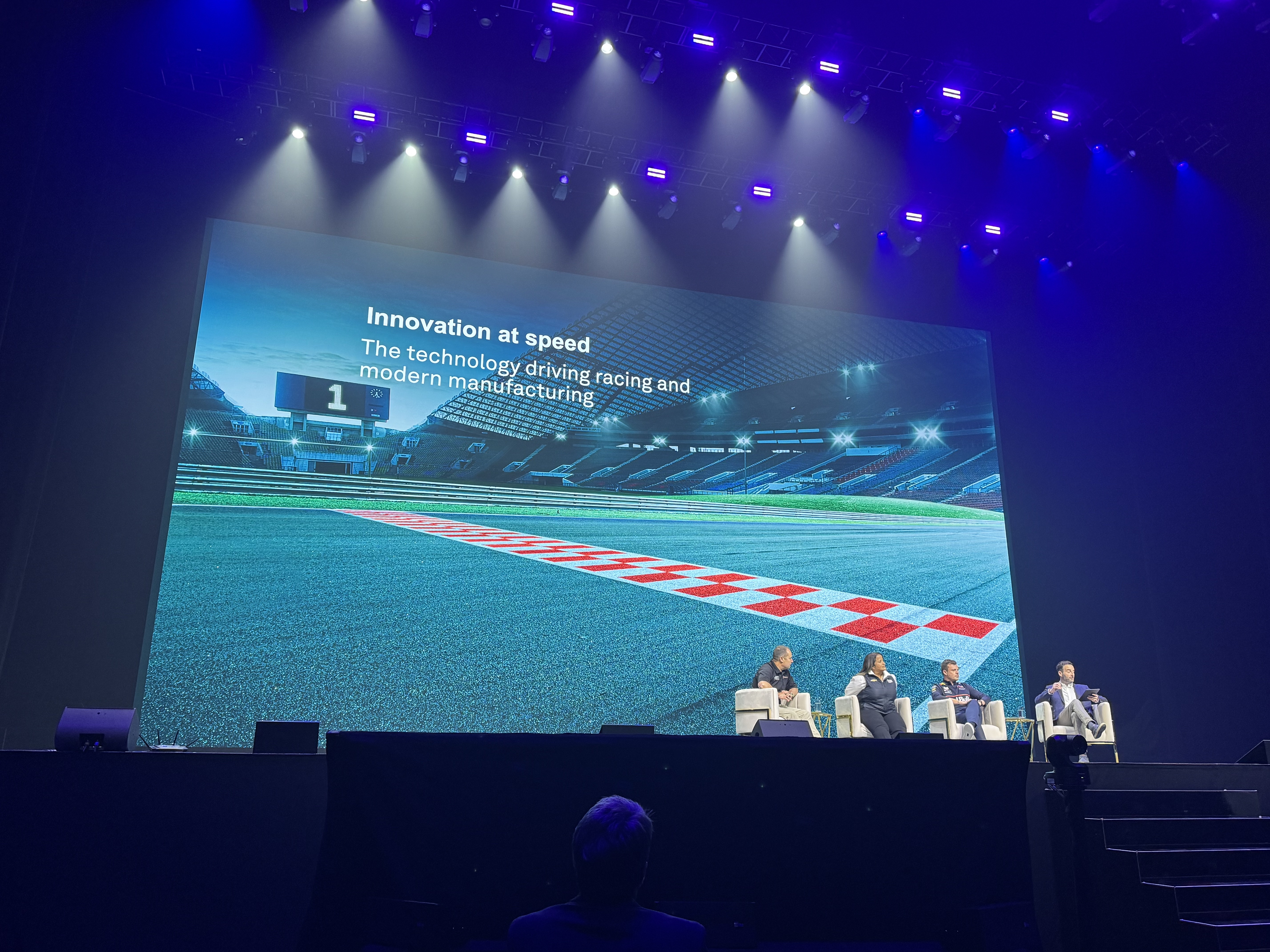 Tech conference panel discussing innovation in racing and manufacturing technology