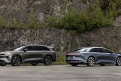Two luxury electric vehicles parked beside rocky cliff with green vegetation