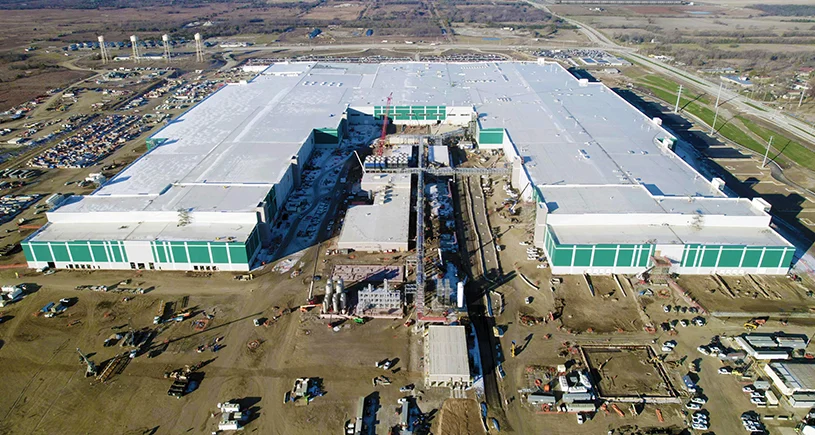 Aerial view of massive industrial complex with white and green buildings under construction