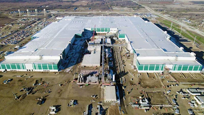 Aerial view of massive industrial complex with white and green buildings under construction