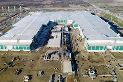 Aerial view of massive industrial complex with white and green buildings under construction