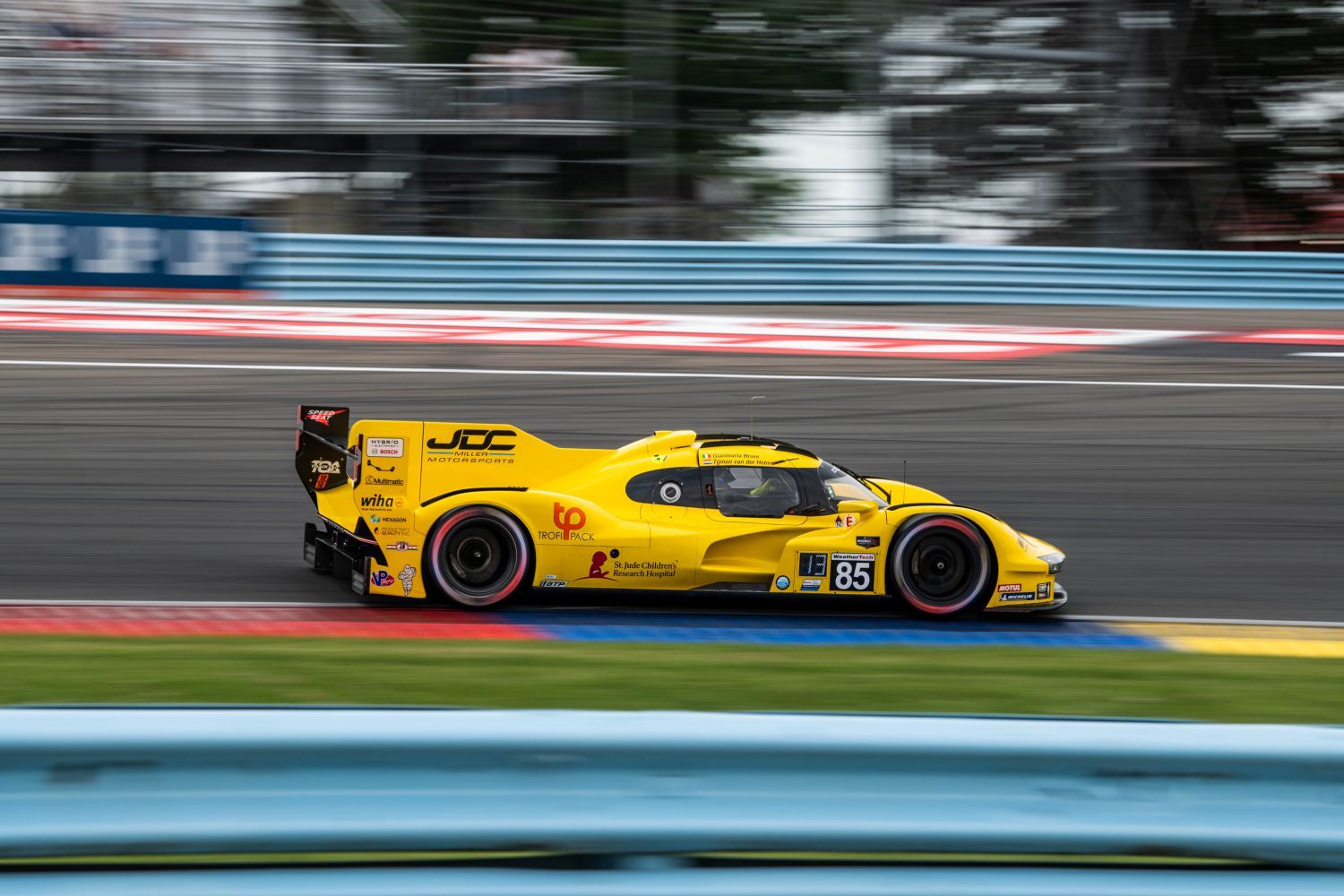 Yellow racing car #85 speeding on professional motorsport track