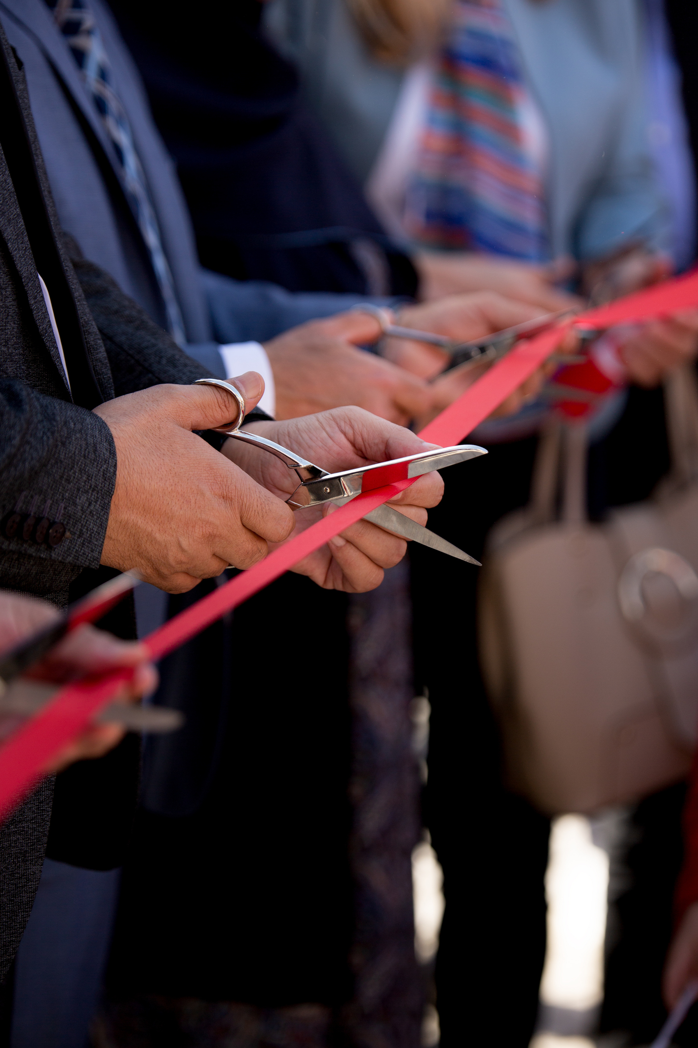 Hands cutting red ribbon at official opening ceremony