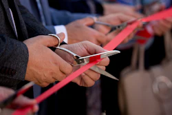 Hands cutting red ribbon at official opening ceremony