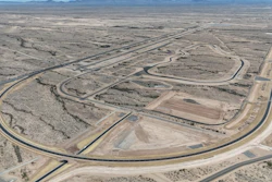 Aerial view of curved racetrack winding through barren desert landscape