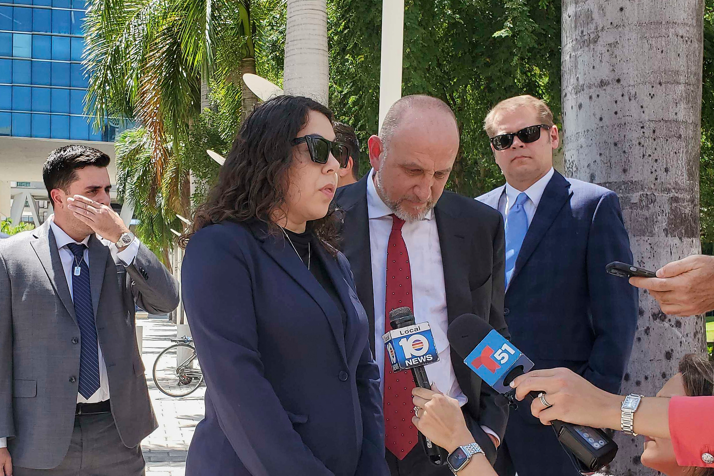 Press conference with officials and journalists outside tropical urban setting