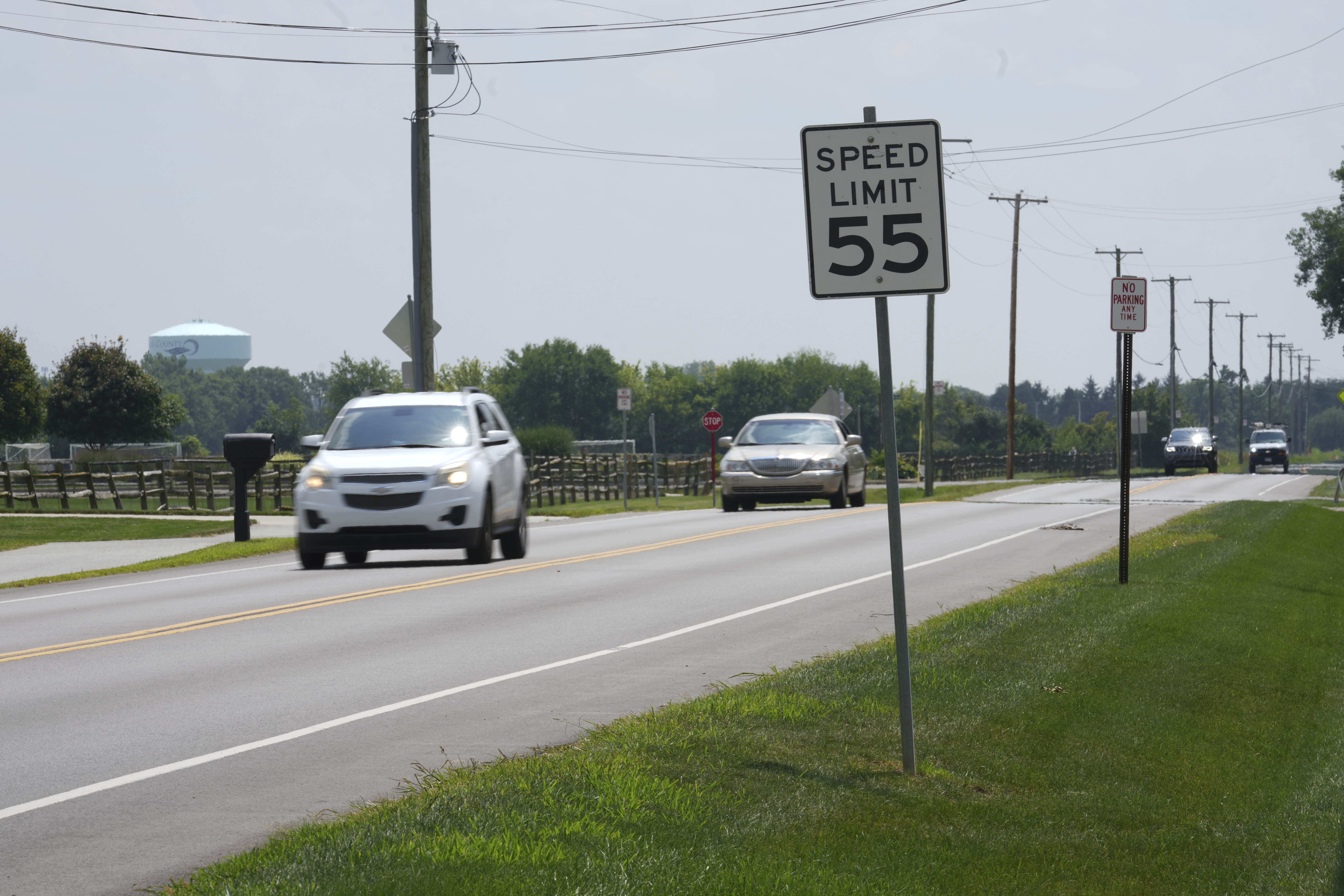 Highway with 55 mph speed limit sign, white and gray vehicles driving on road