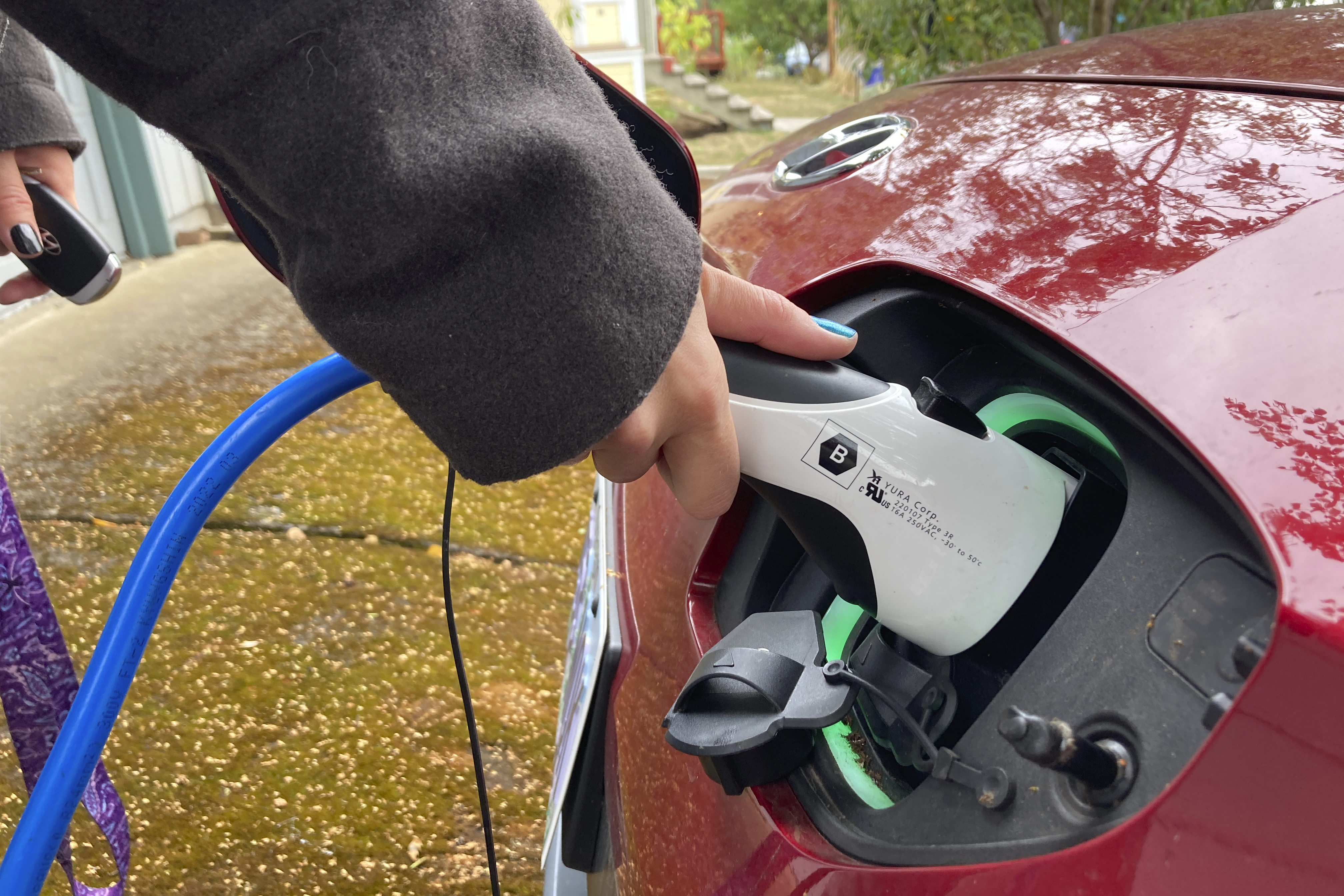 Red electric vehicle being charged with blue charging cable