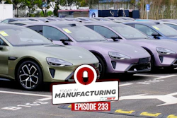 Multiple electric vehicles in green and purple parked in a manufacturing lot