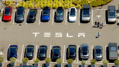 Aerial view of Tesla parking lot with multiple electric vehicles in various colors