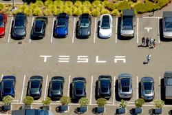 Aerial view of Tesla parking lot with multiple electric vehicles in various colors