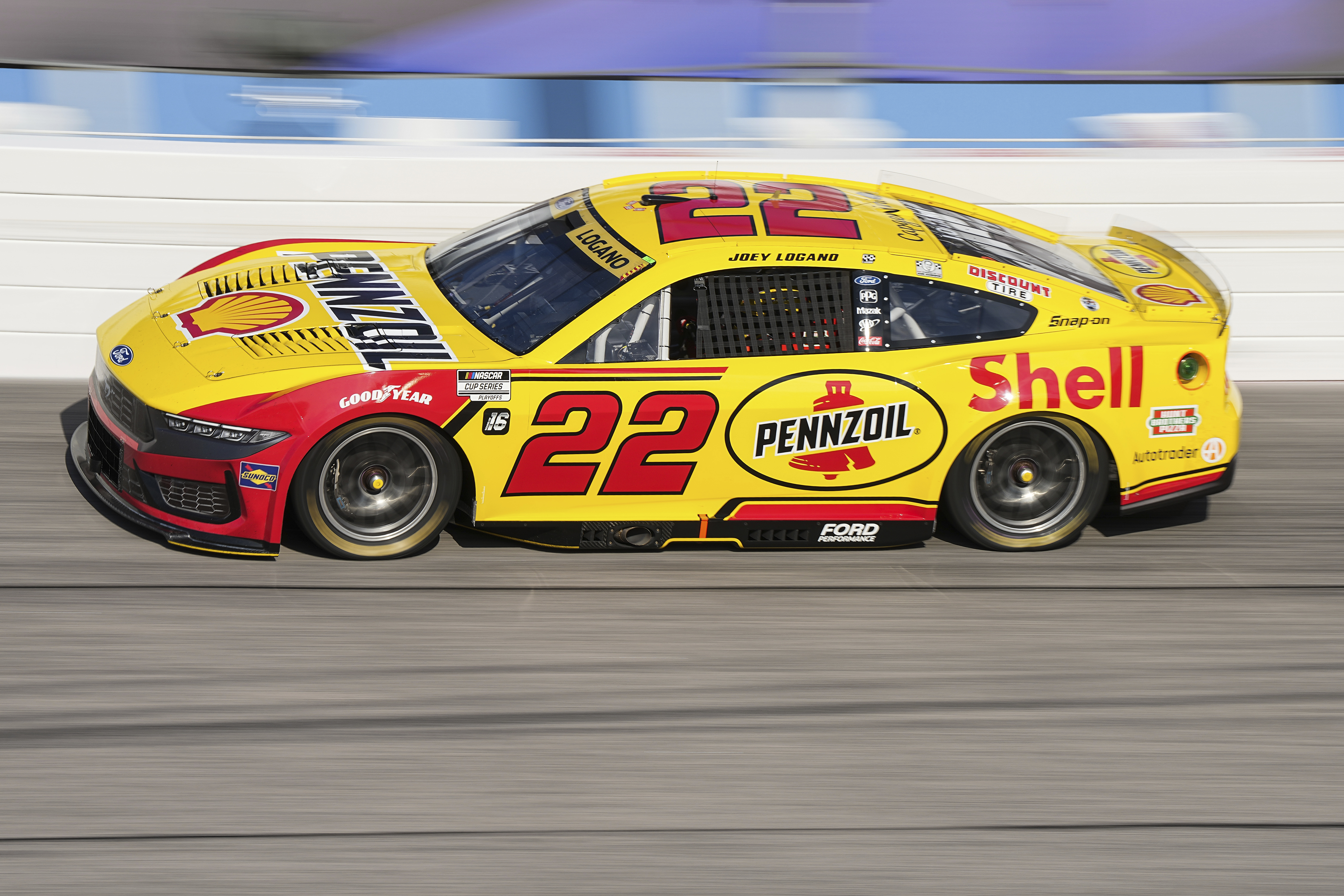 Yellow NASCAR race car with Shell and Pennzoil sponsorship speeding on track