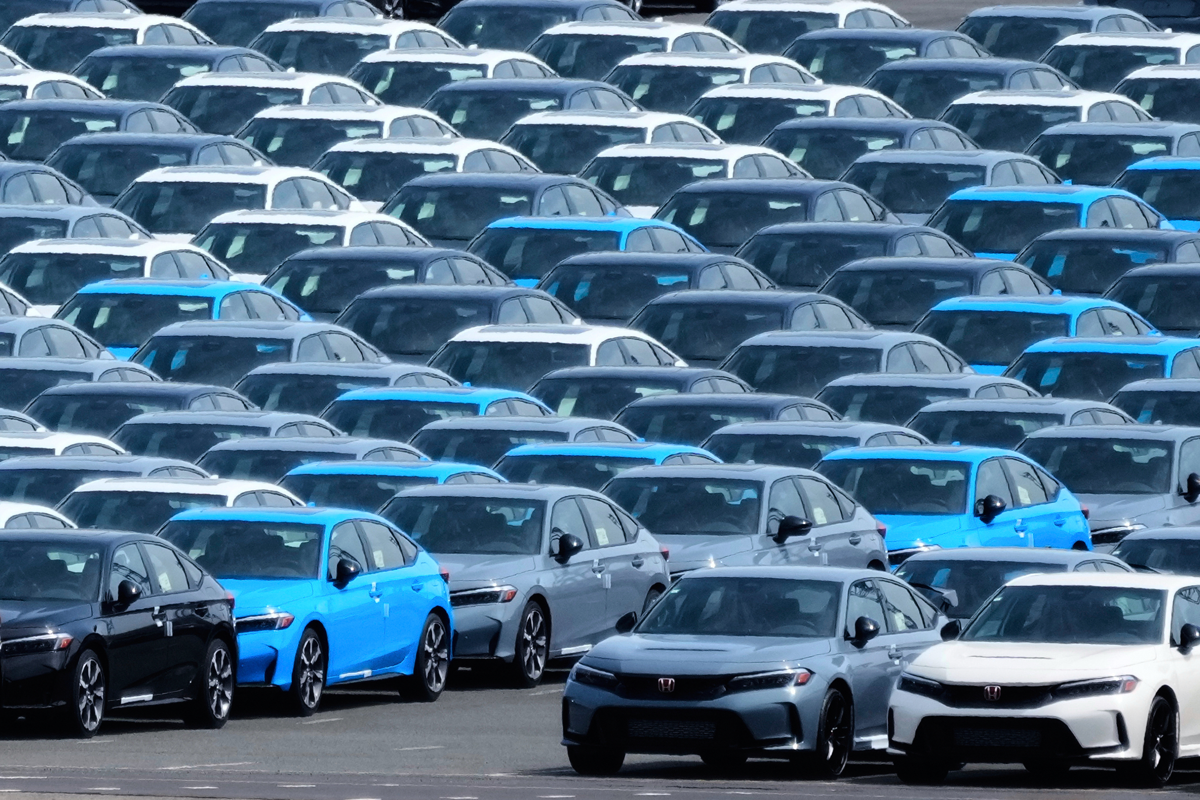 Large parking lot filled with new blue and gray Tesla electric vehicles