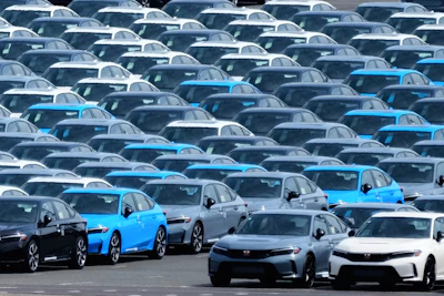 Large parking lot filled with new blue and gray Tesla electric vehicles